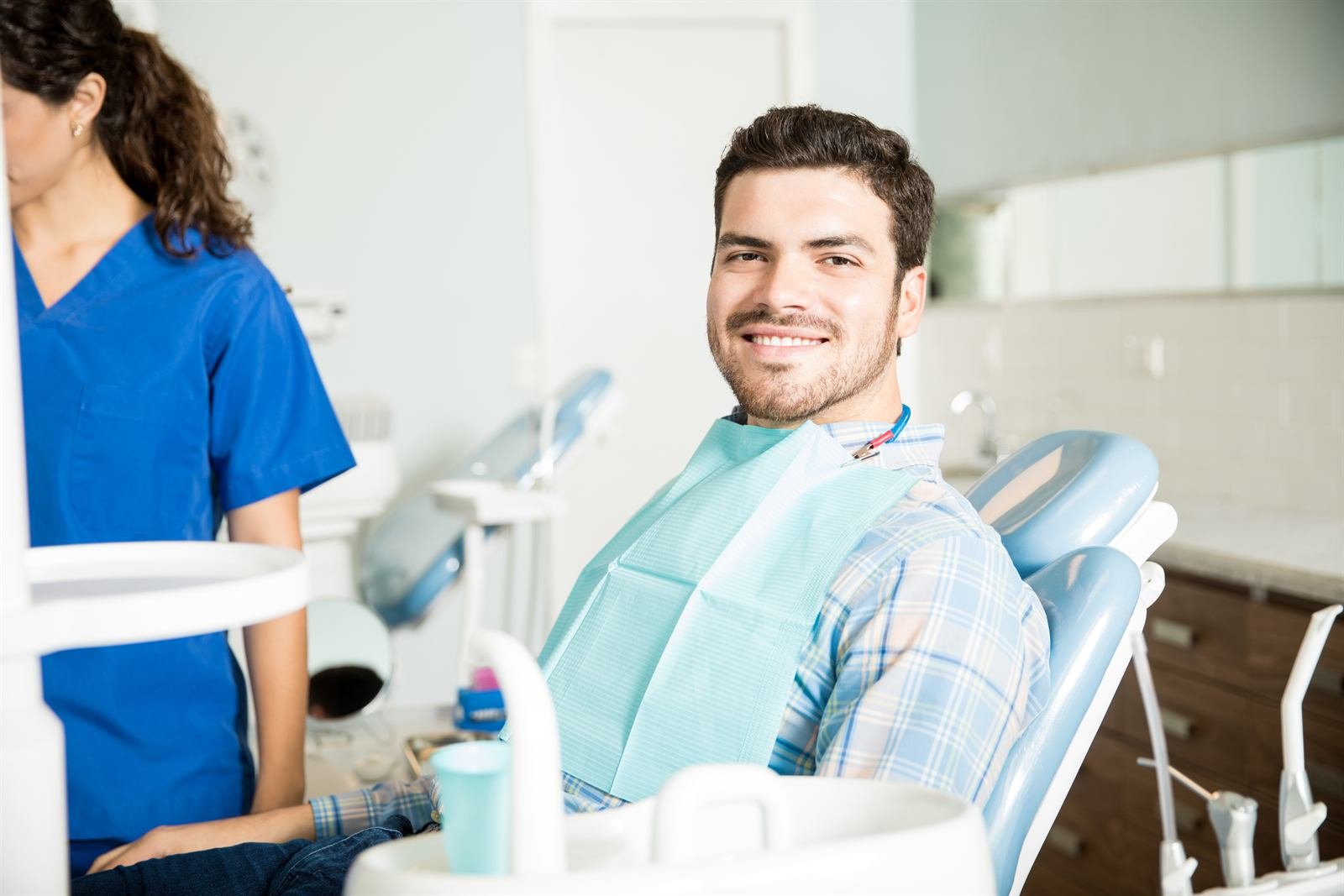 Paciente sonriendo en el sillón dental junto a una asistente
